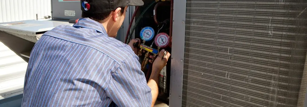 HVAC technician servicing a condenser unit in Clarks Summit